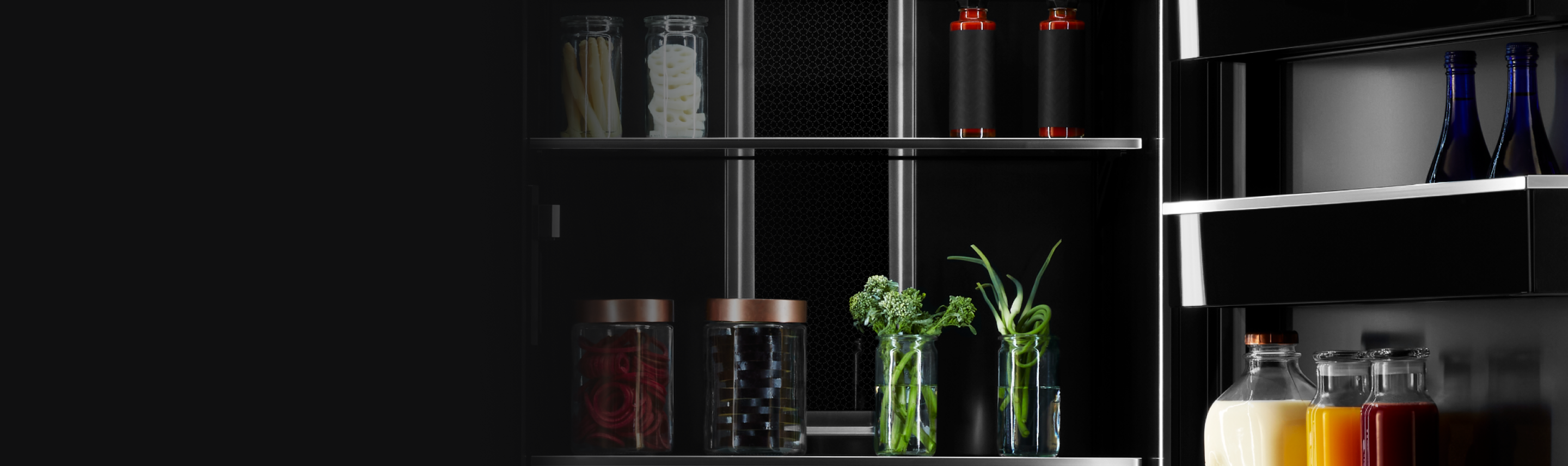 Intérieur d’un réfrigérateur JennAir rempli d’articles comme des fines herbes dans des verres, des boissons et des condiments.